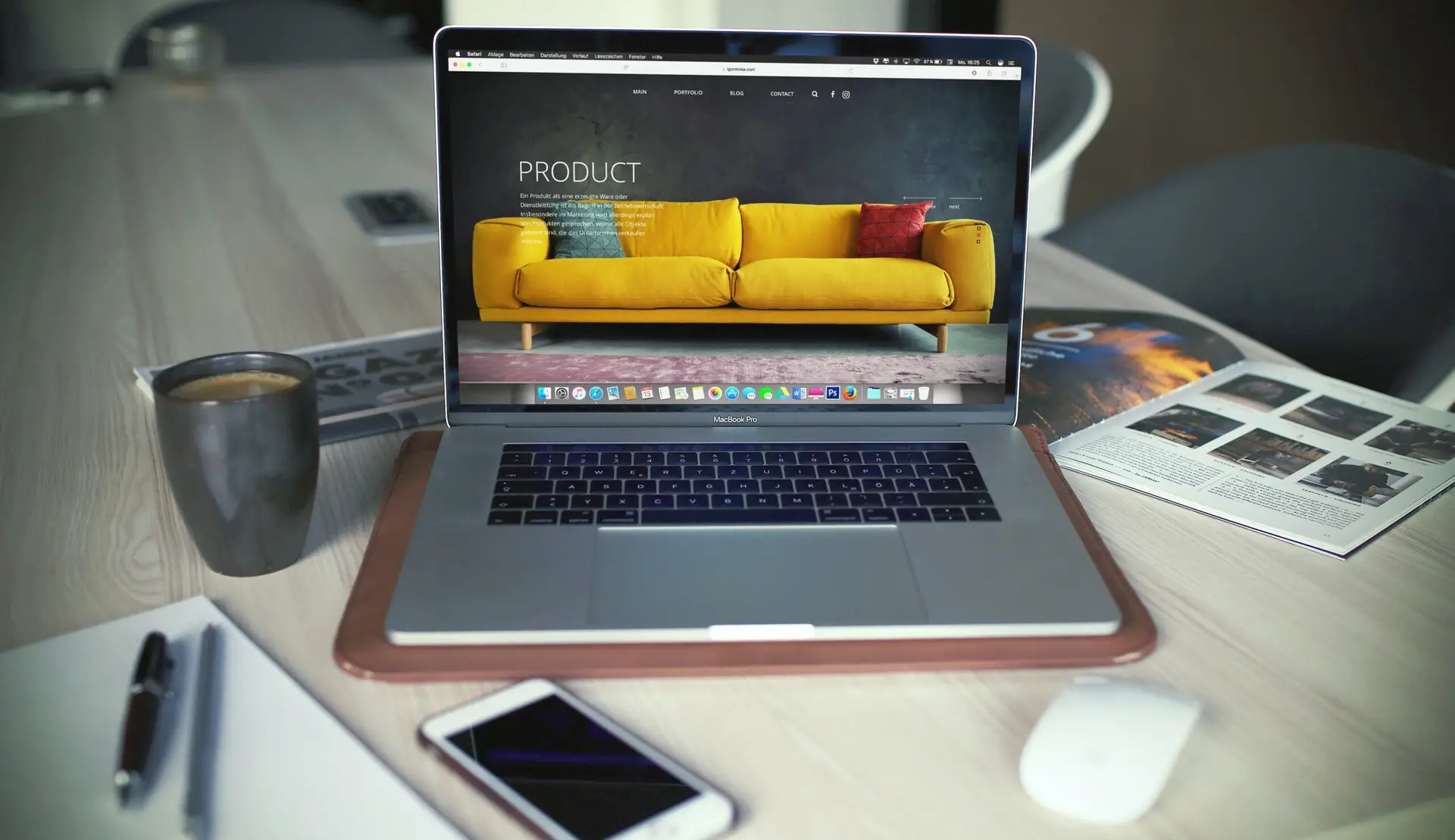 Laptop displaying product website design on desk with coffee and phone
