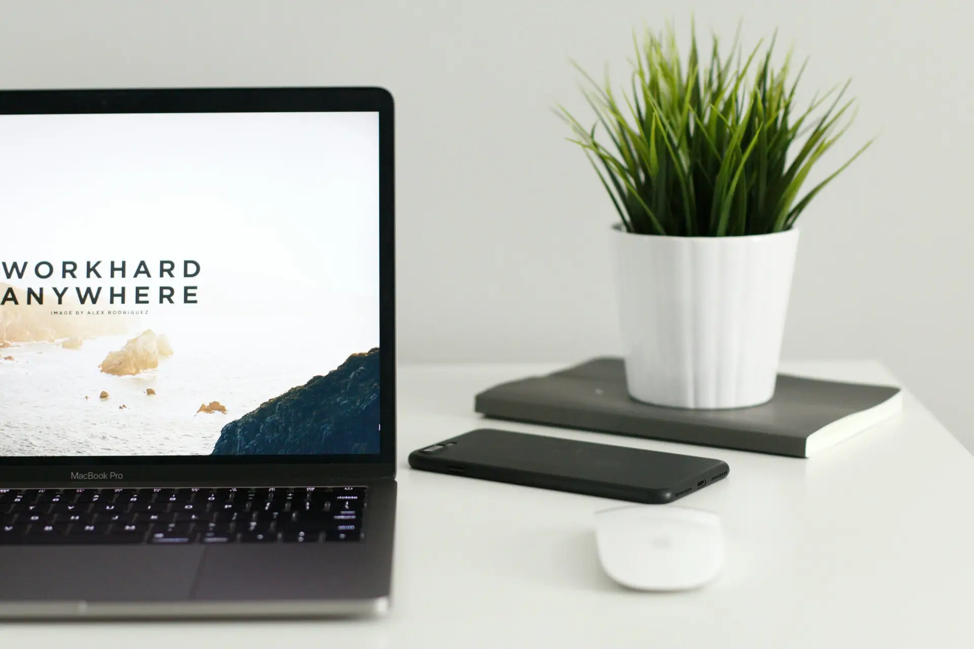 Minimal desk setup with laptop smartphone mouse and plant